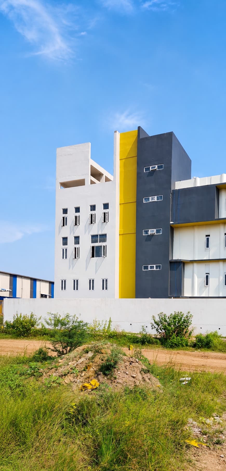 Exterior corner — the stair-tower's charcoal and yellow accent